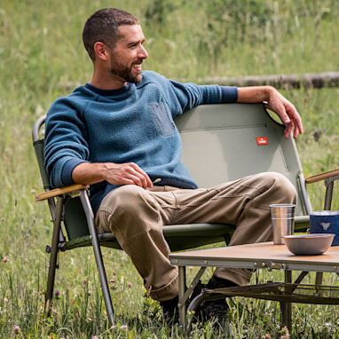 Person using compact chair outdoors table nearby
